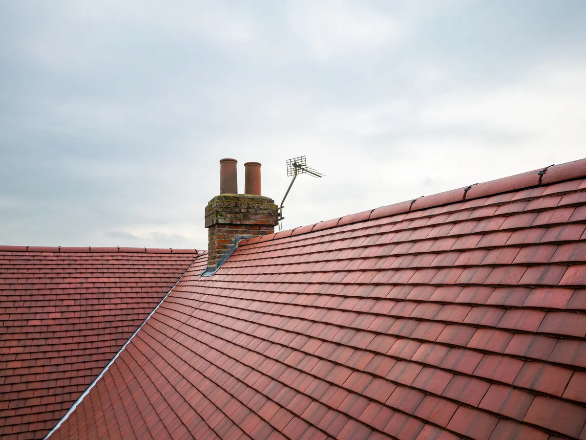 A newly completed pitched roof with clay tiles and chimney stack