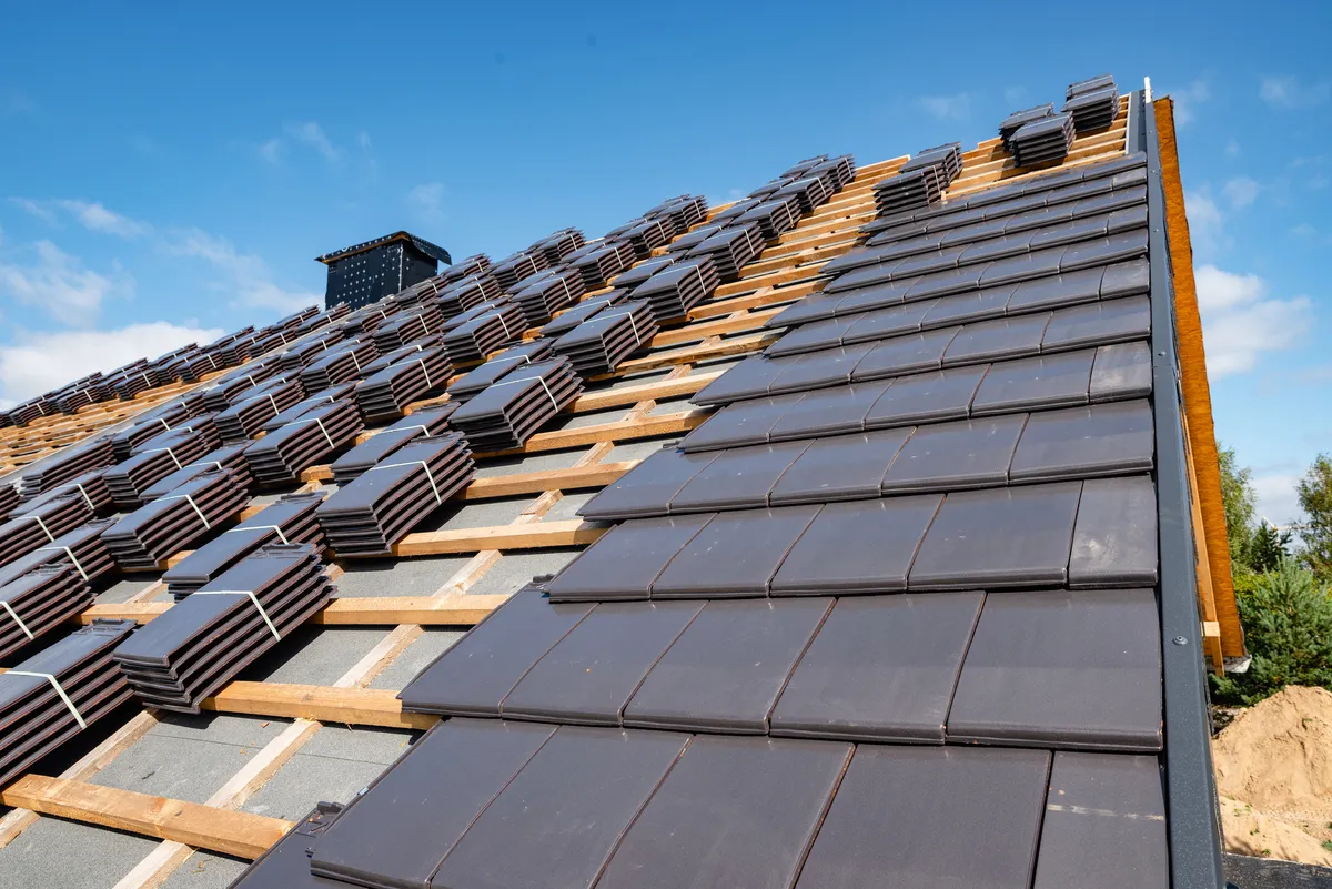 New concrete roof tiles being laid on timber battens during a full re-roof
